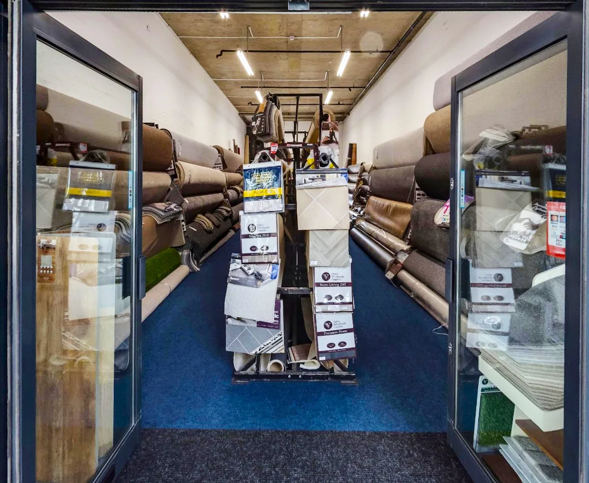 C&M Carpets showroom entrance with flooring rolls and sample stands